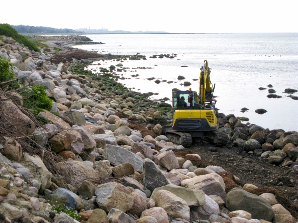 Erosionsmaterial mot havet. Natursten lavas med grävmaskin så att havets erodering av strandlinjen försvåras...